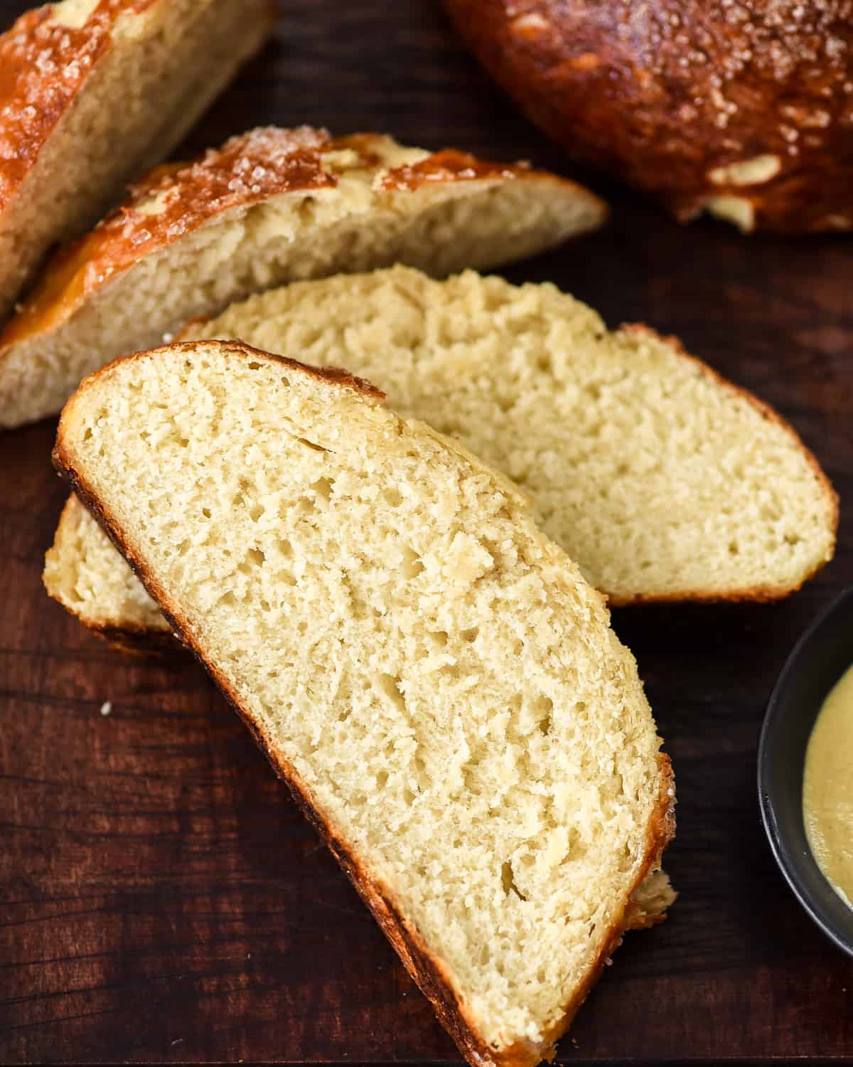 Overhead view of three slices of homemade pretzel bread on a cutting board