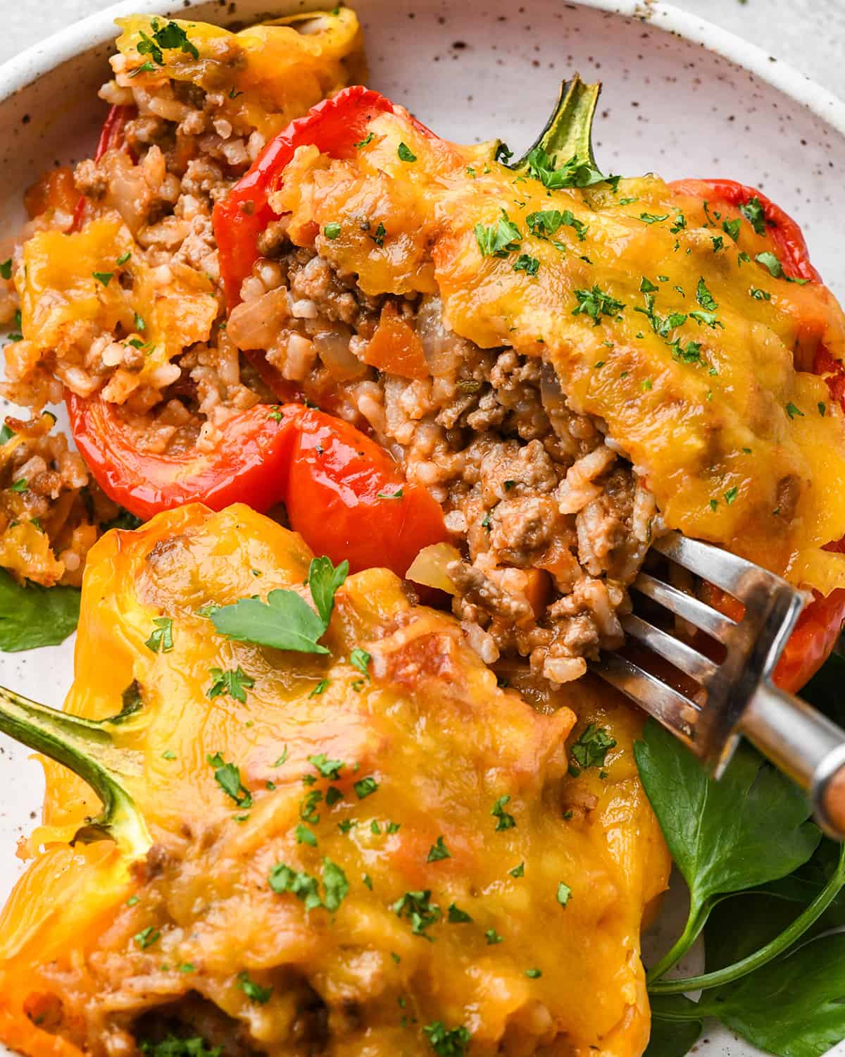 a fork taking a bite of stuffed bell peppers on a plate