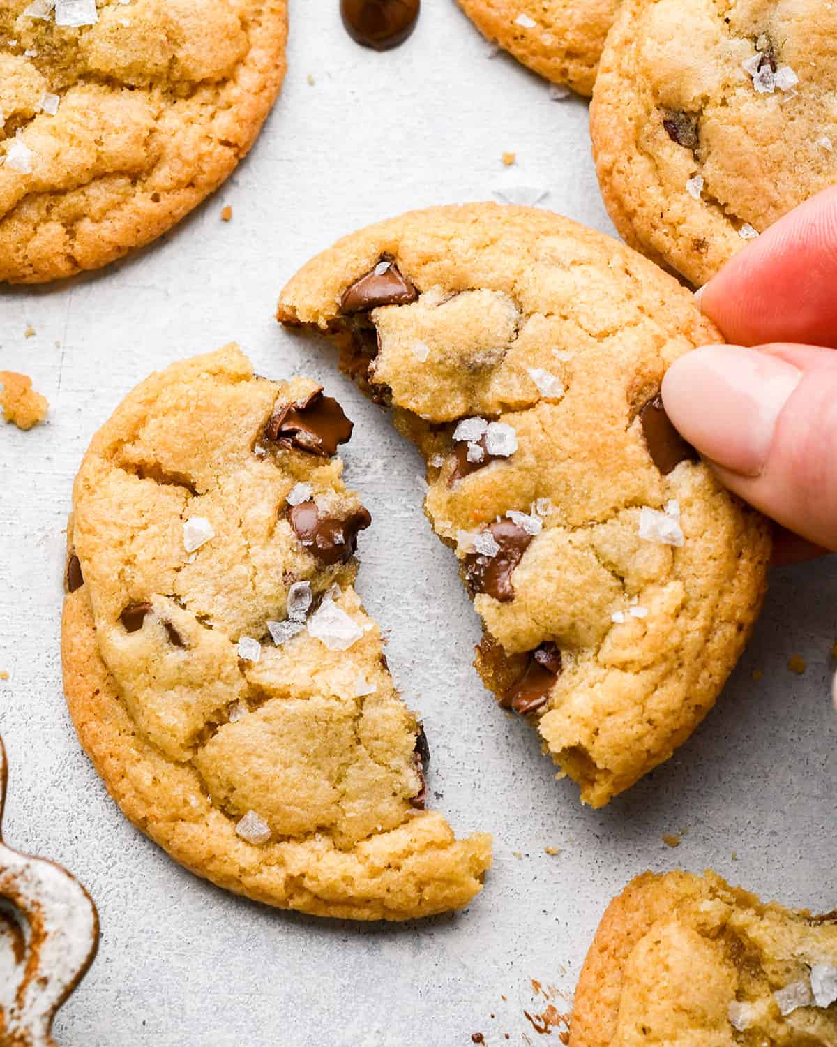 a hand holding a half of a Brown Butter Chocolate Chip Cookie. 