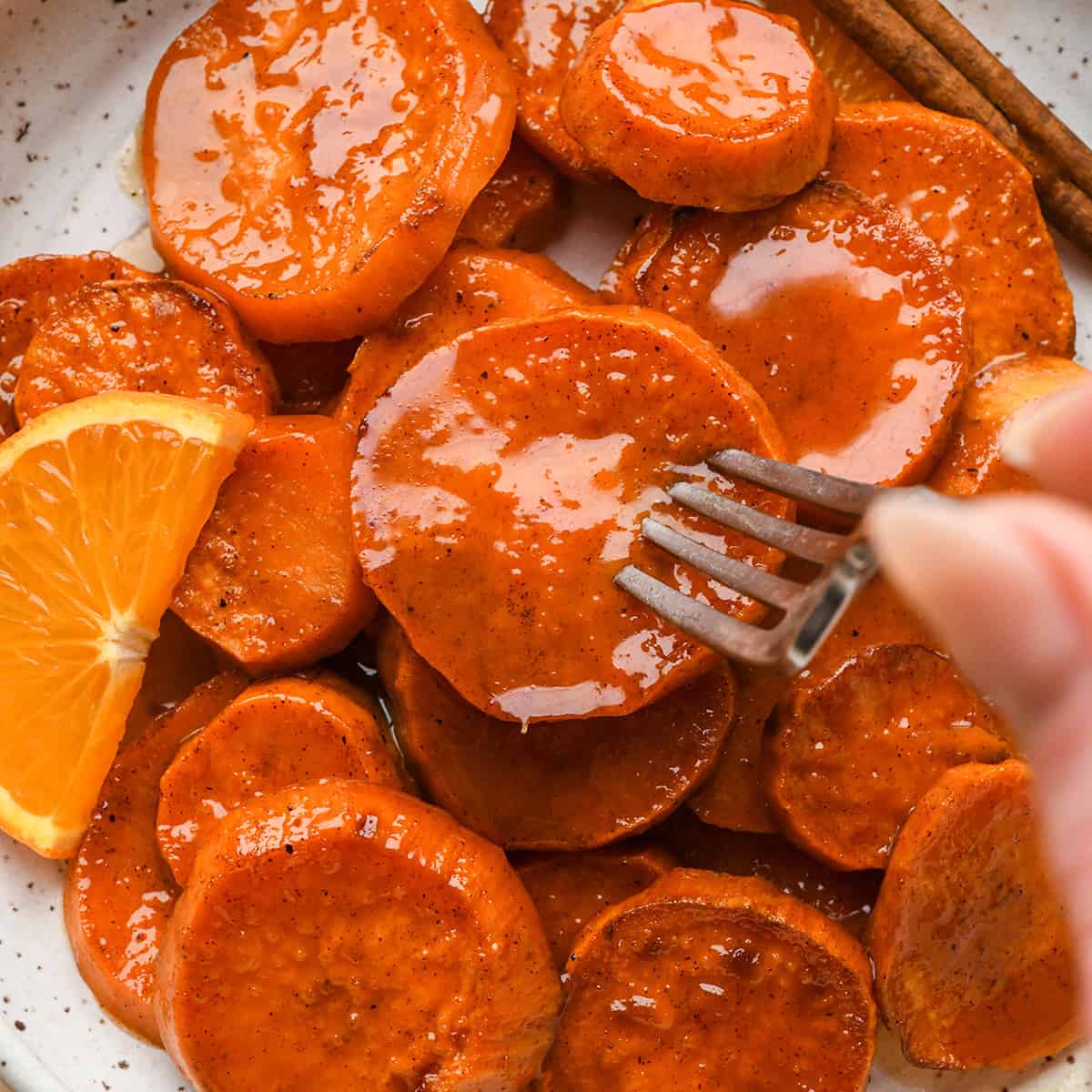 a fork taking a bite of Candied Yams on a plate