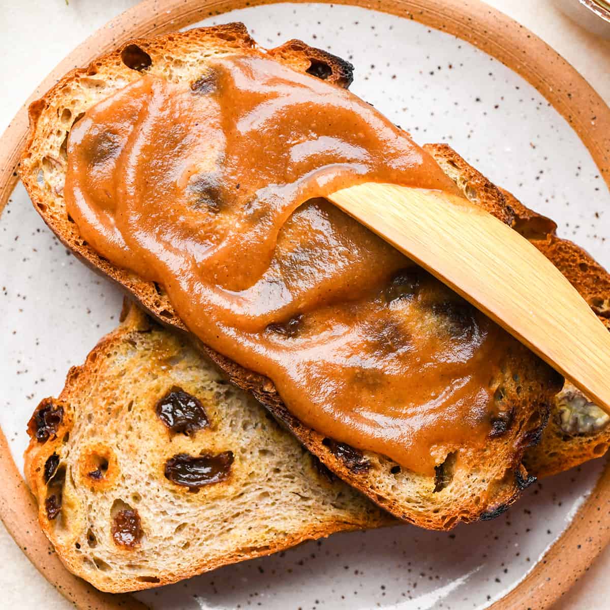 Apple Butter being spread on top of a piece of toasted raisin bread