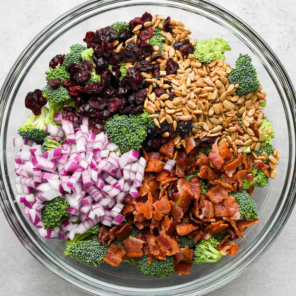 assembling Broccoli Salad in a large glass bowl