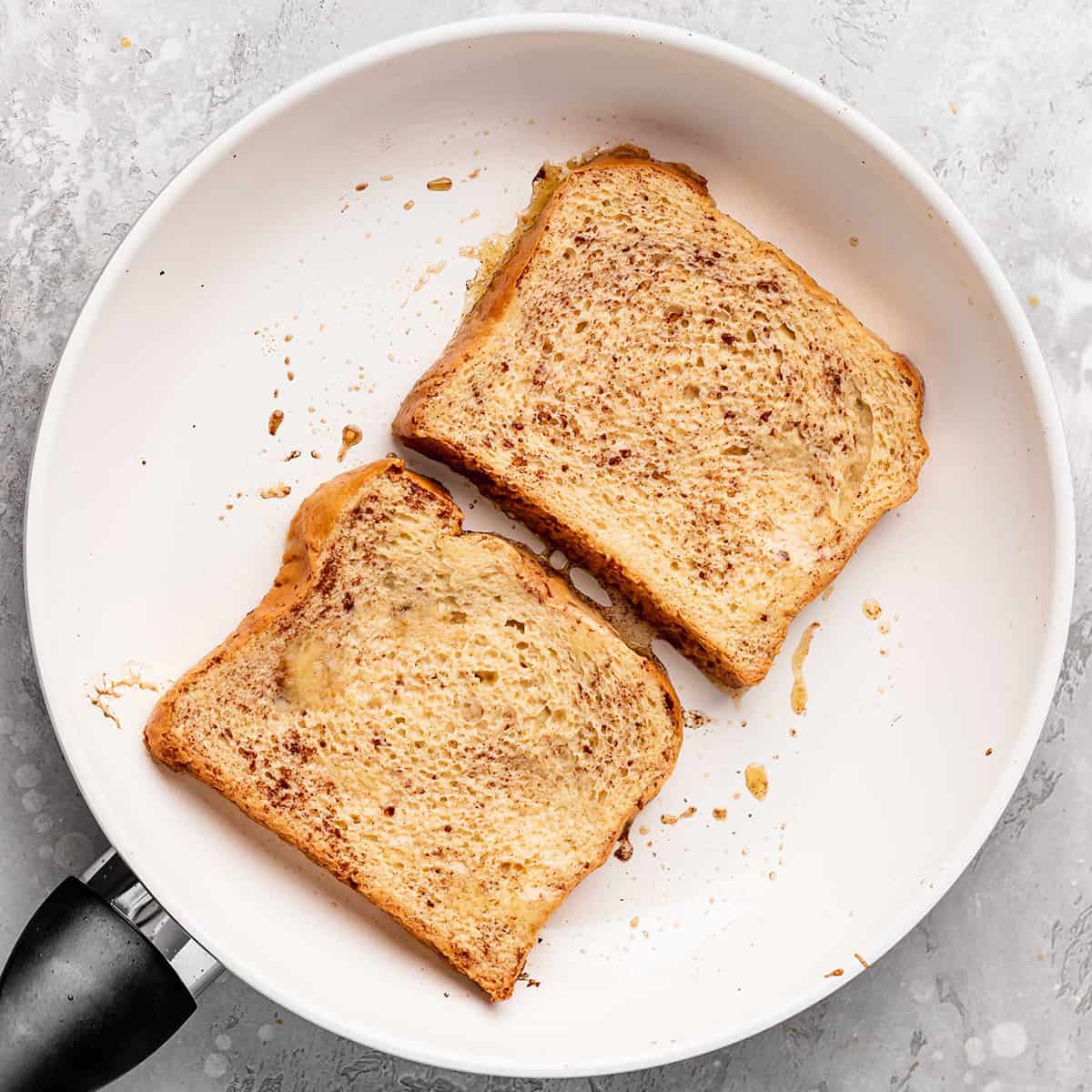 french toast in a frying pan being cooked on the first side