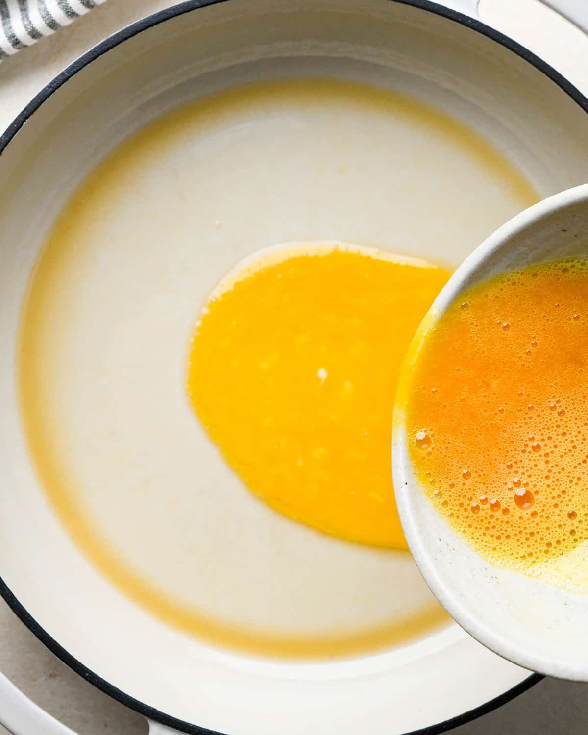 eggs being poured into a pan with sesame oil