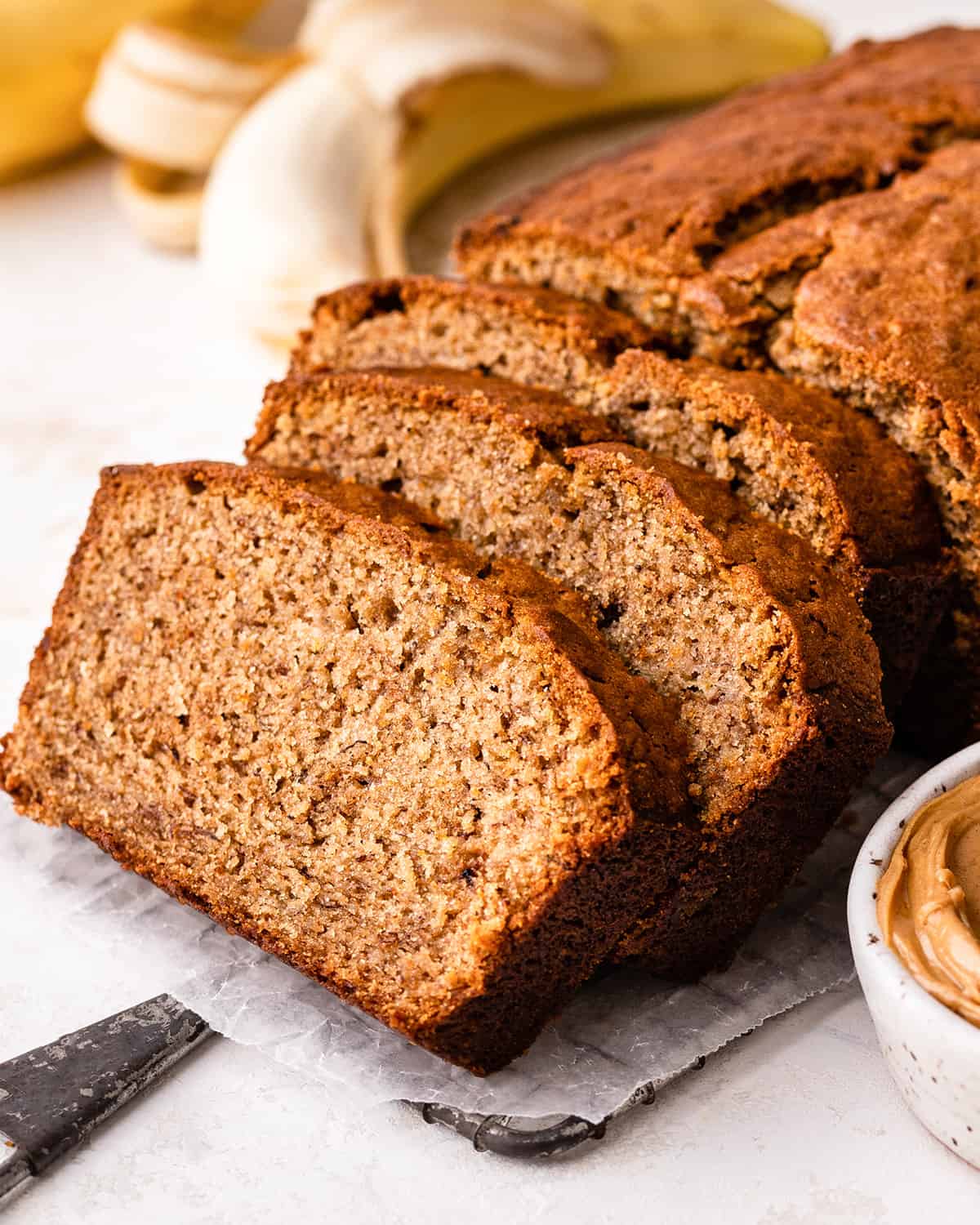 front view of a loaf of Peanut Butter Banana Bread with 3 slices cut out of it leaning on each other 