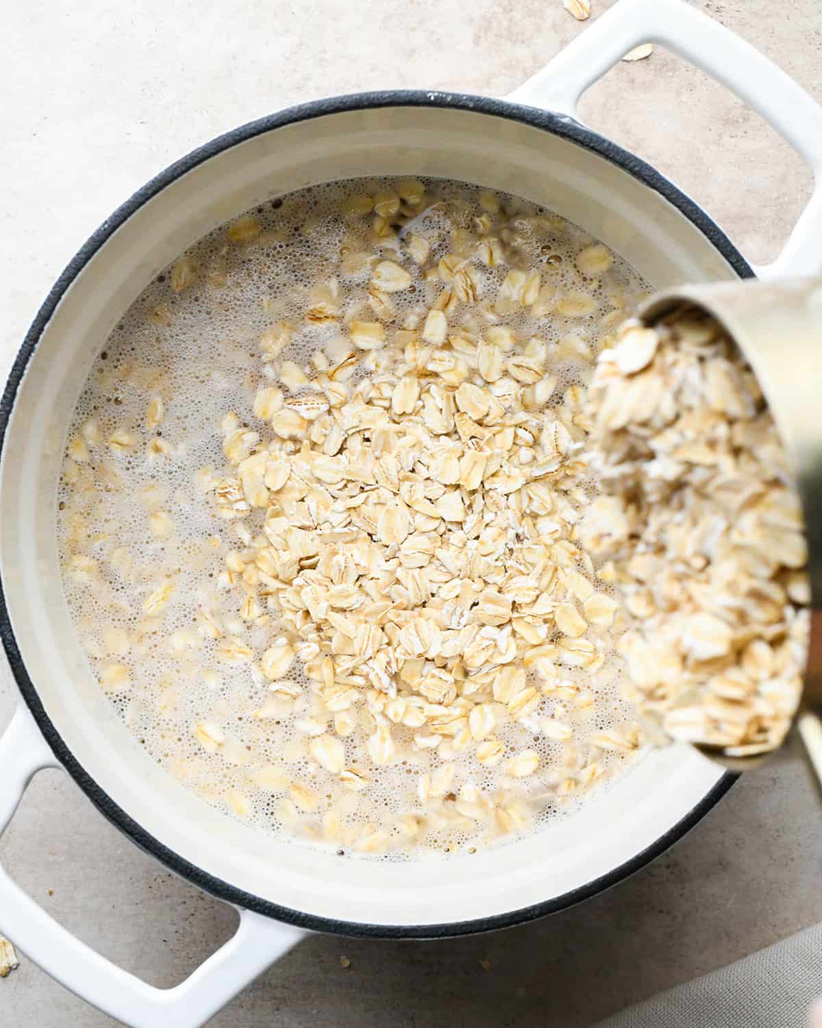 oatmeal being poured into a pan with boiling water to make Peanut Butter Oatmeal