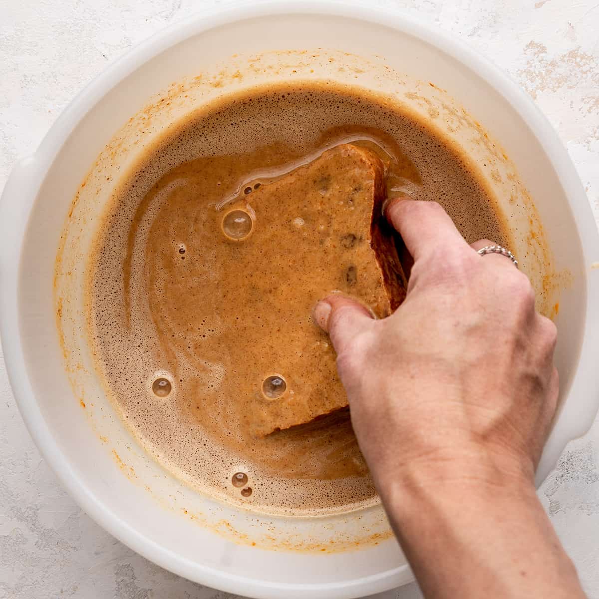 bread being dipped into the Pumpkin French Toast mixture